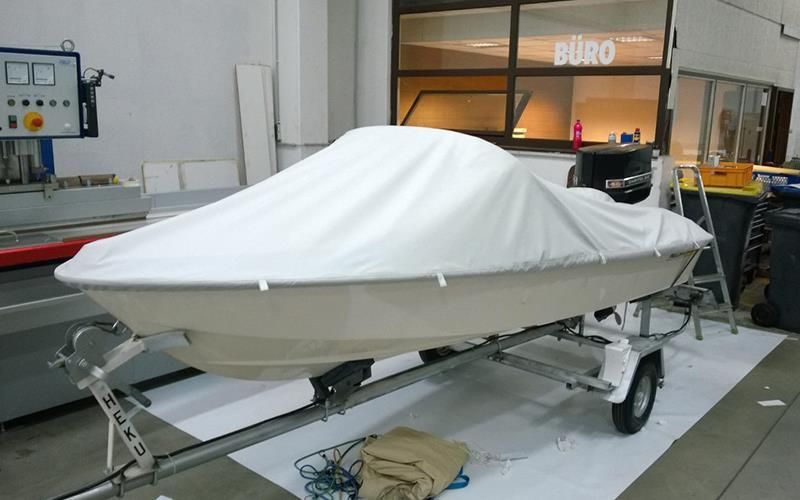Ein Boot auf einem Anhänger mit einer weißen Abdeckung darauf