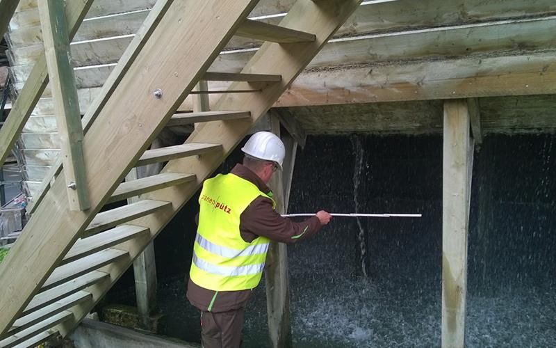Ein Mann in einer gelben Weste misst eine Holztreppe