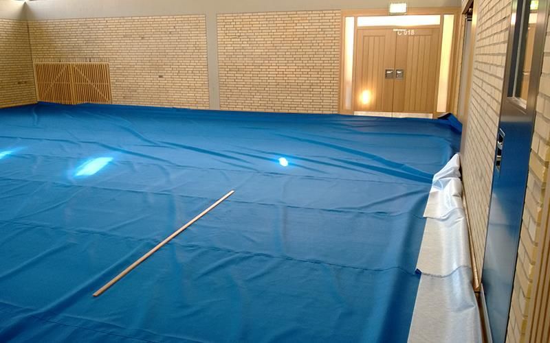 Eine blaue Plane bedeckt den Boden einer Turnhalle