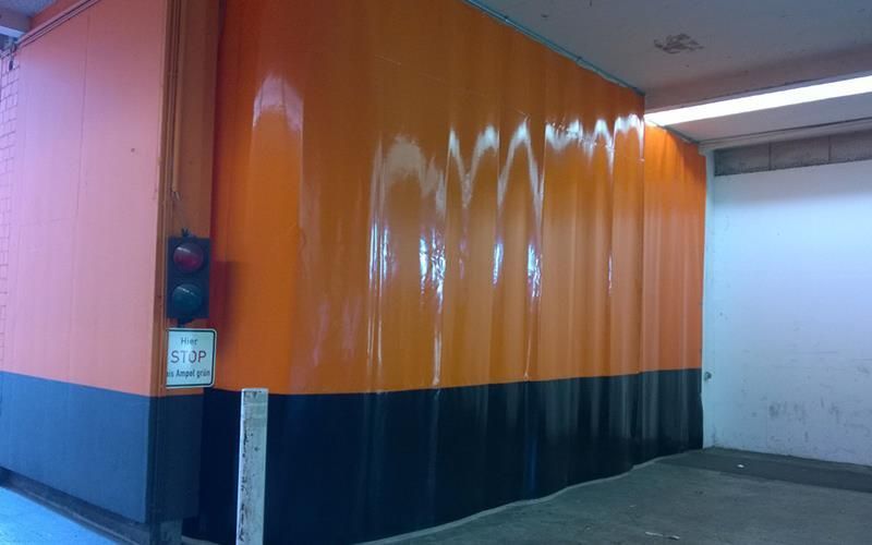 Eine orange-schwarze Wand mit Graffiti in einem Parkhaus.