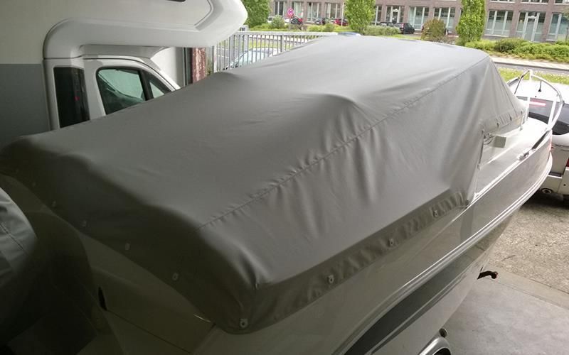 In einer Garage ist ein Boot mit einer weißen Plane abgedeckt.