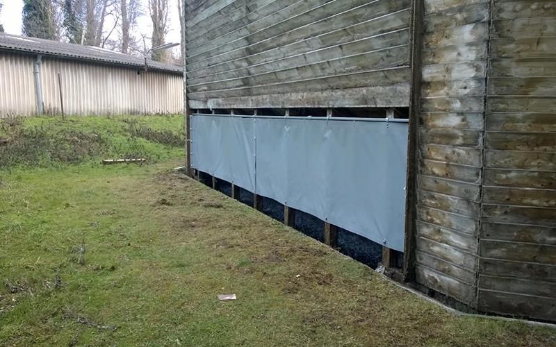 Ein Holzgebäude mit einer blauen Plane an der Seite.