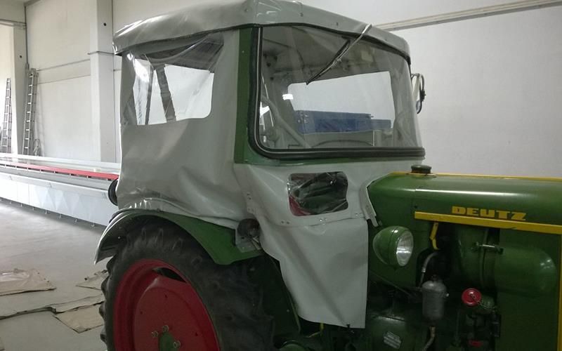 Ein grün-weißer Deutz-Traktor steht in einer Lagerhalle