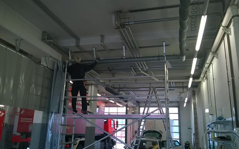 Ein Mann steht auf einem Gerüst in einer Garage.