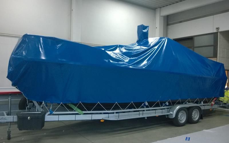 Eine blaue Plane bedeckt ein Boot auf einem Anhänger