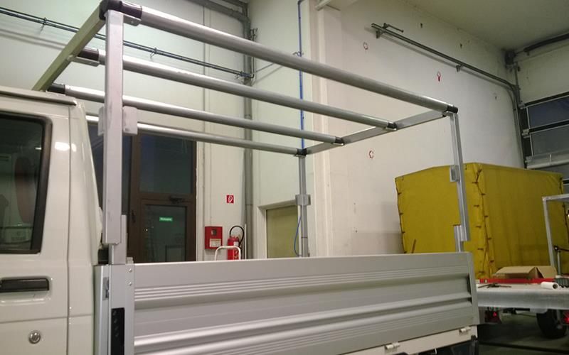 Ein weißer Lastwagen mit einem Verdeck auf der Rückseite steht in einer Garage.