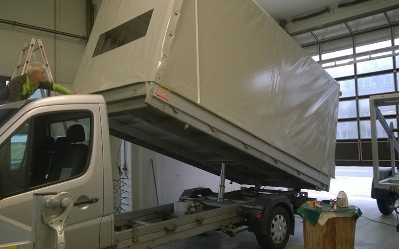 Ein weißer Lastwagen mit einem Verdeck steht in einer Garage.