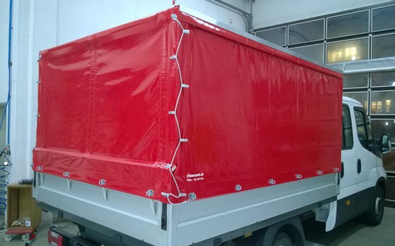 Ein LKW mit einem roten Verdeck steht in einer Garage.