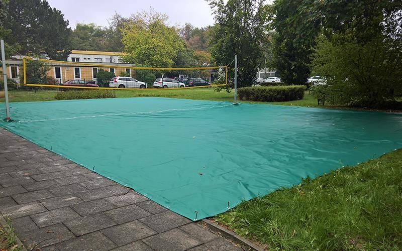 Ein Volleyballfeld ist mit einer grünen Plane überdacht.