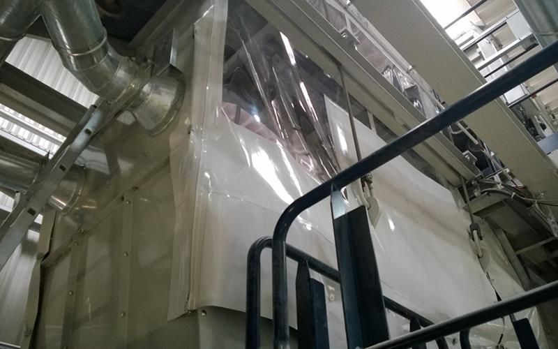 In einer Fabrik ist eine große Maschine mit Plastik abgedeckt.