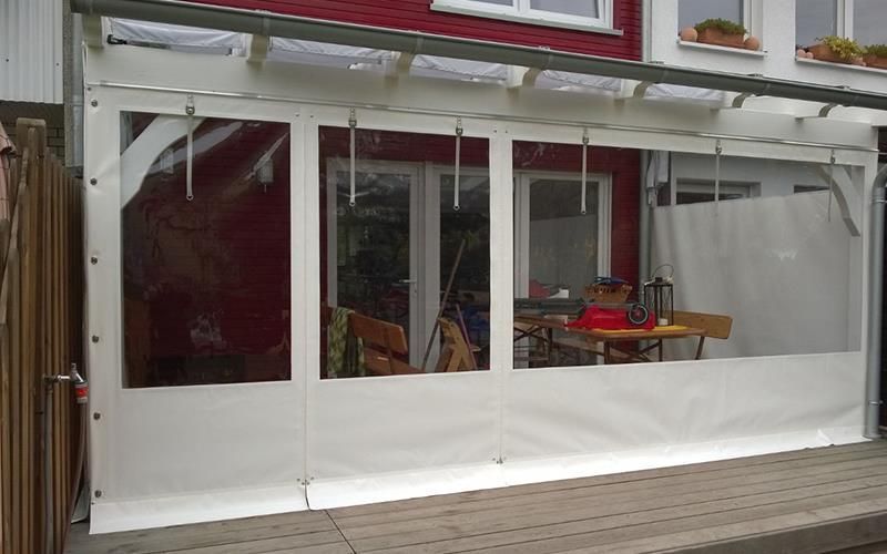 Eine weiße Plane bedeckt eine Terrasse mit einem Tisch und Stühlen.