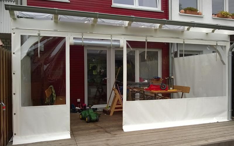 Eine weiße Plane bedeckt eine Terrasse vor einem roten Haus.