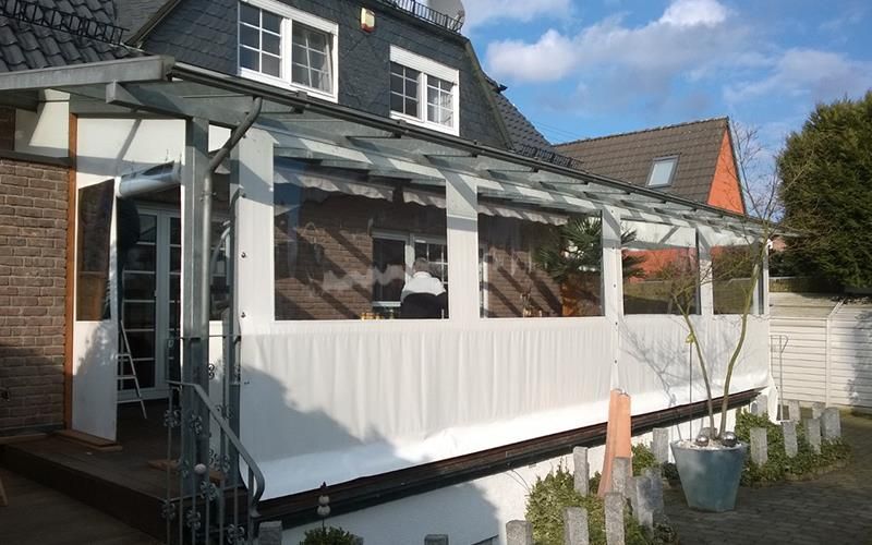 Ein Haus mit einer weißen Veranda und einem Glasdach.