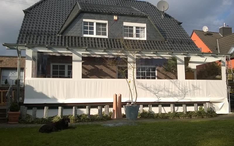 Ein Haus mit einem schwarzen Dach und einer weißen Veranda