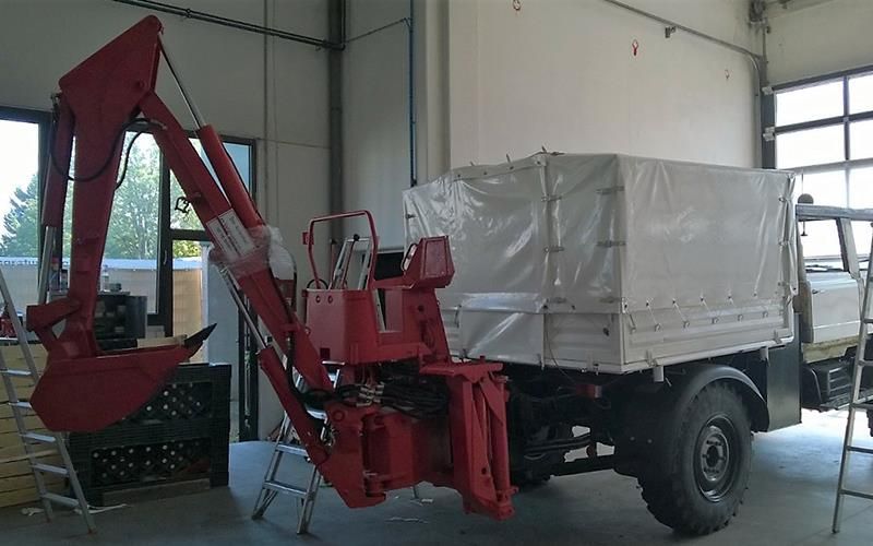 Ein roter Lastwagen mit einem daran befestigten Kran steht in einer Garage.