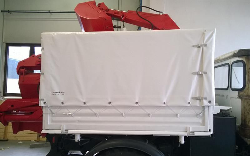 Ein roter LKW mit einer weißen Plane auf der Rückseite