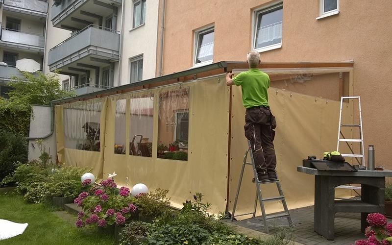 Ein Mann steht auf einer Leiter vor einem Gebäude.