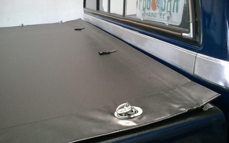 Ein blauer LKW mit einer schwarzen Laderaumabdeckung