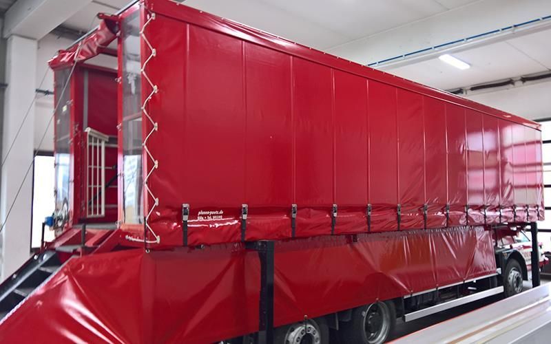 Ein roter Lastwagen steht auf einer Hebebühne in einer Garage.