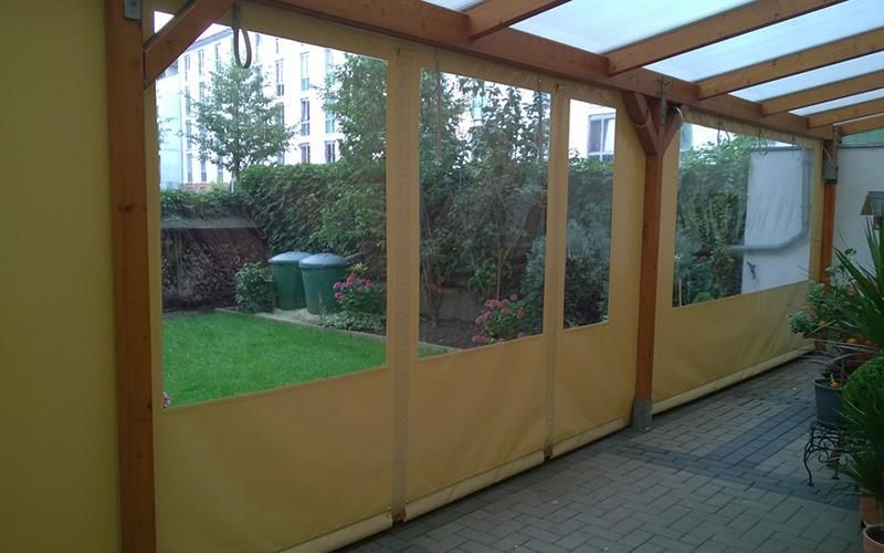 Eine Pergola mit vielen Fenstern und Blick auf einen Garten.
