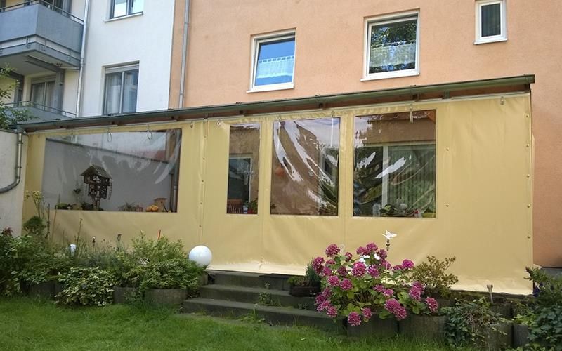 Ein Haus mit überdachter Veranda und Blumen davor.