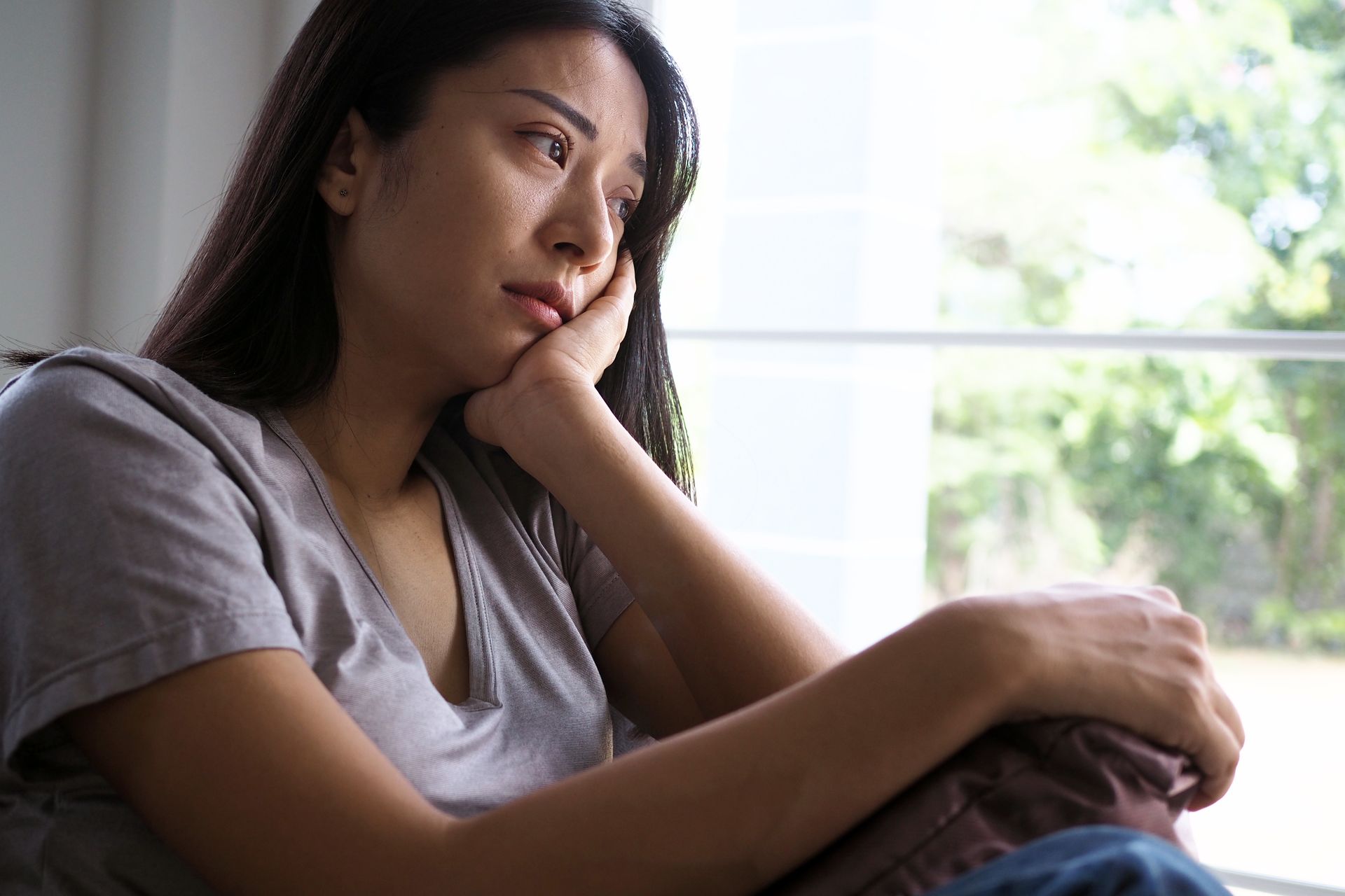 Femme triste assise sur le rebord d'une fenêtre