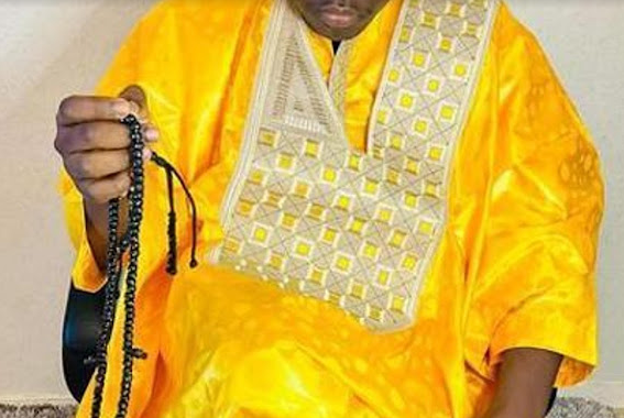 Marabout vêtu d'un vêtement jaune et tenant un collier de perles noires