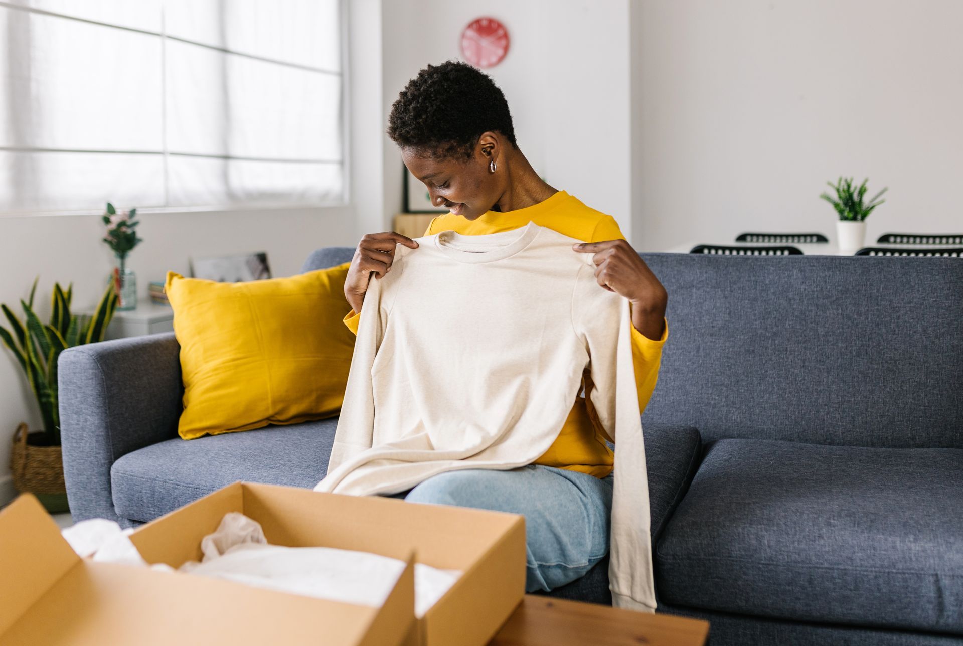 Jeune femme qui ouvre son colis de vêtement.