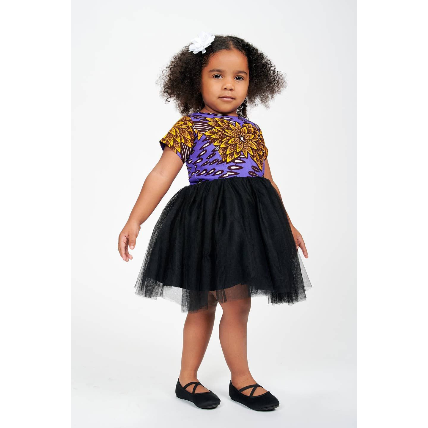 Petite fille avec haut en wax violet et jupe en tulle noire.