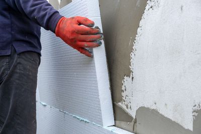 Arbeiter bringt Aussenwanddämmplatten an einer Gebäudefassade an