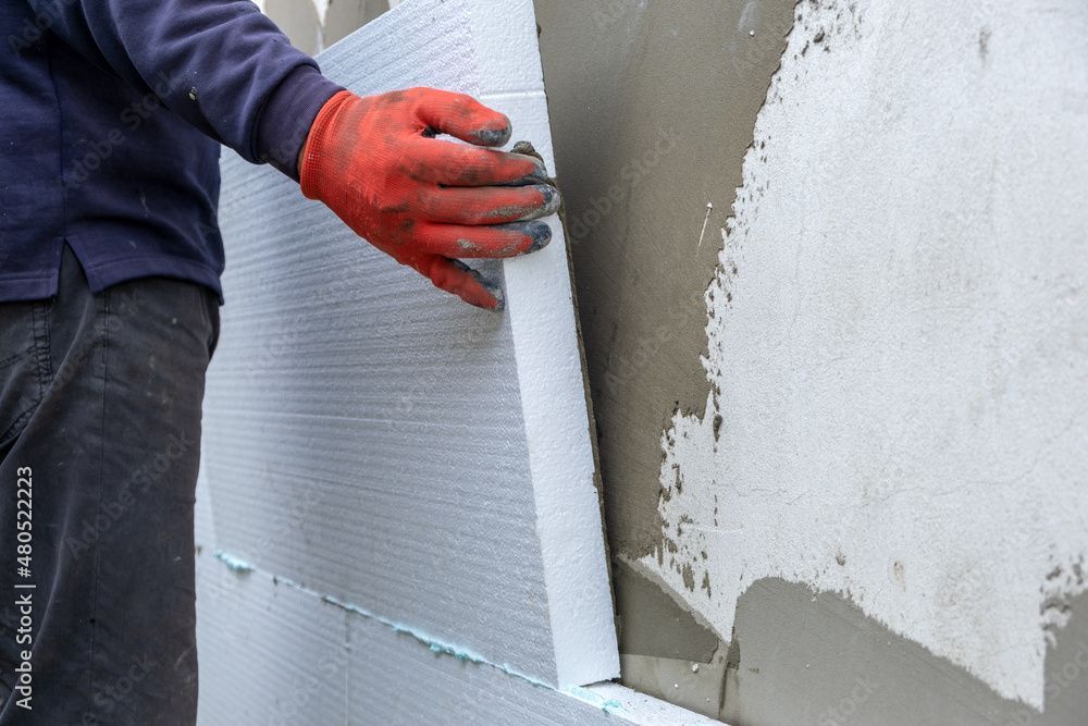 Arbeiter bringt Aussenwanddämmplatten an einer Gebäudefassade an