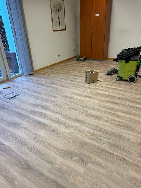 Ein Mann mit orangefarbenen Handschuhen verlegt einen Holzboden.