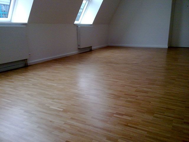 Ein leerer Raum mit Holzboden und weißen Wänden