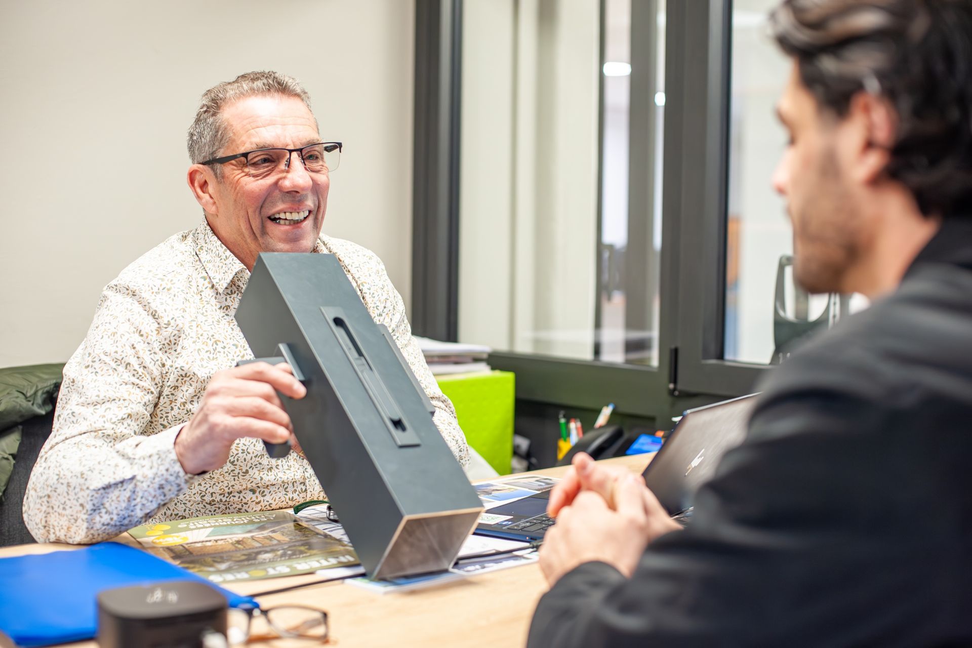 Homme qui fait voir une pièce de menuiserie à un autre homme.