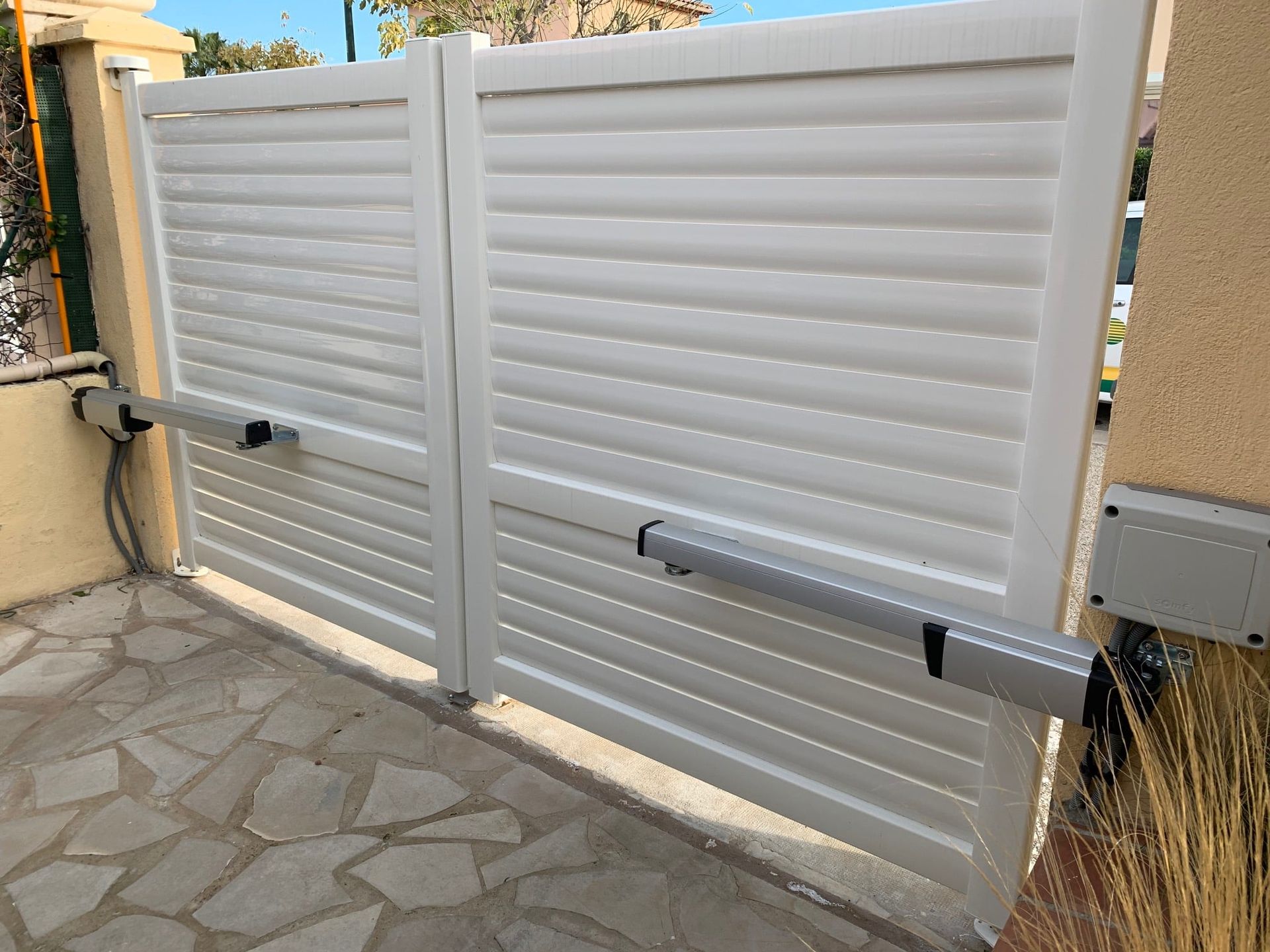 Portail battant blanc motorisé.