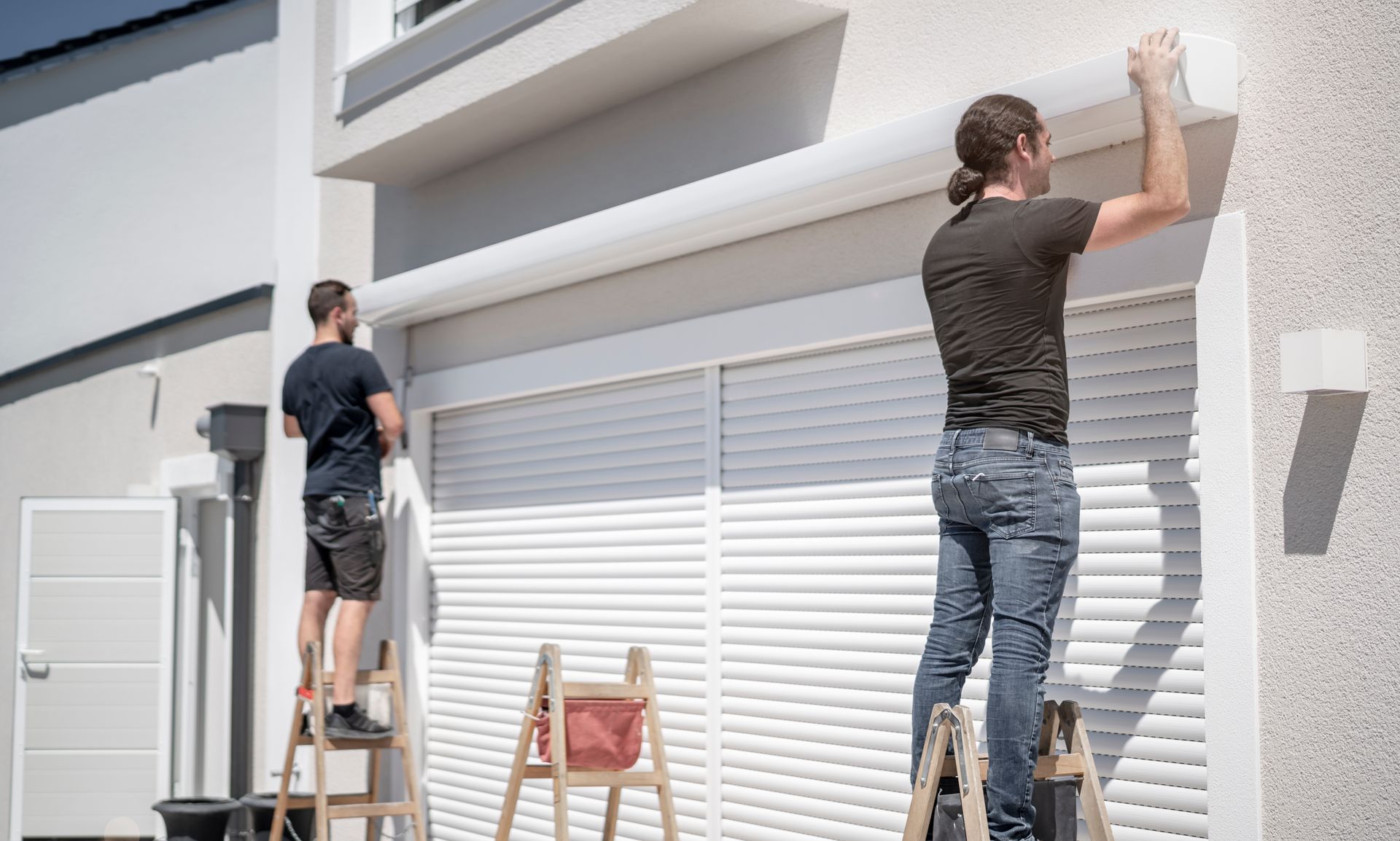 Deux hommes qui installent un store banne.