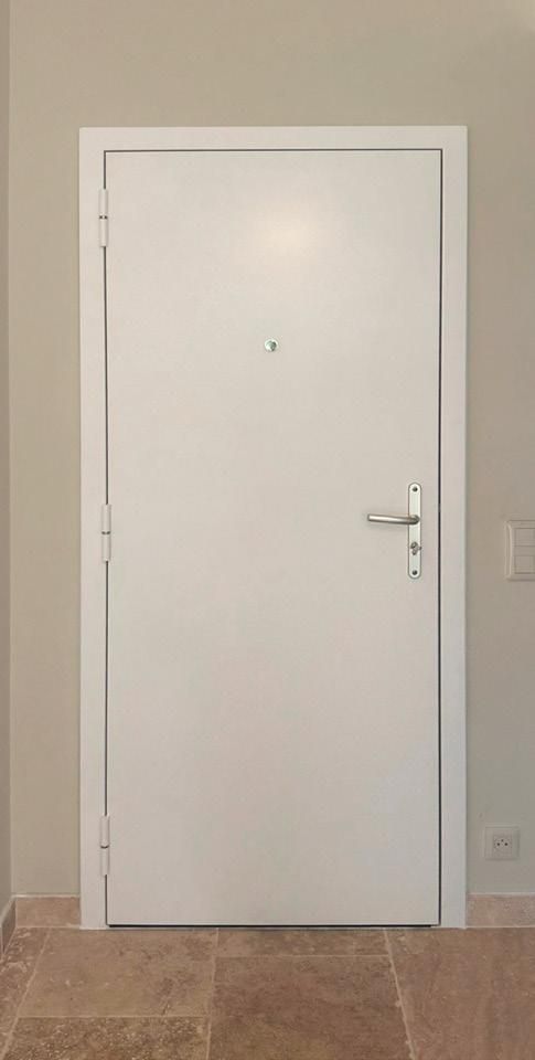 Porte intérieure blanche avec poignée argentée centrée sur un mur beige et un parquet.