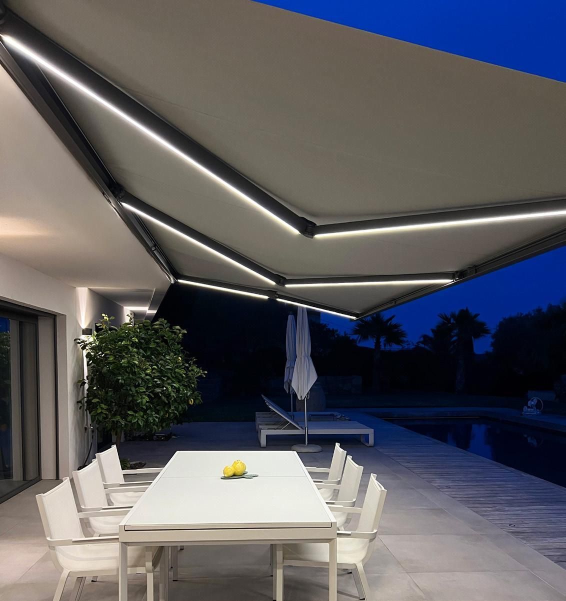 Terrasse extérieure avec table et chaises blanches sous un auvent rétractable au crépuscule