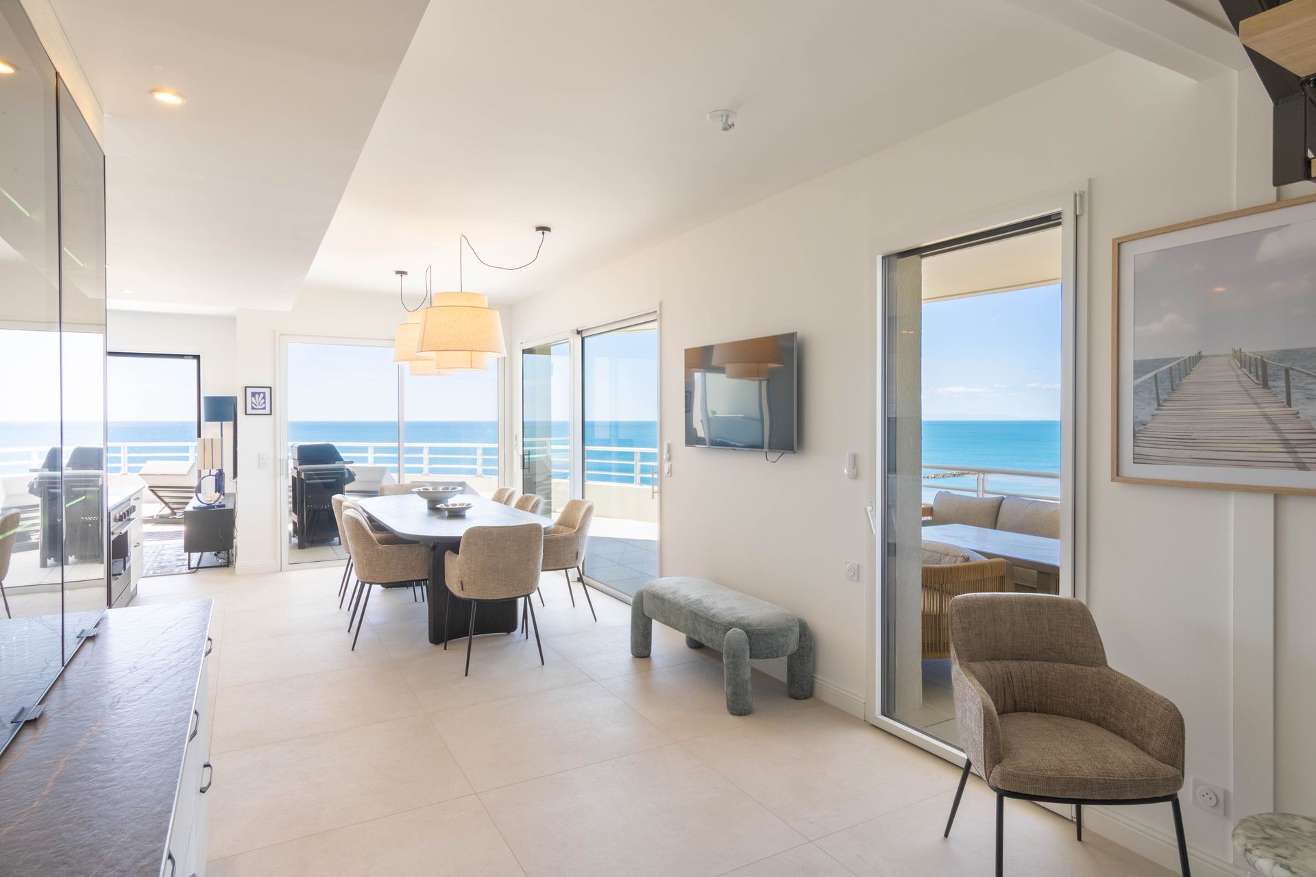 Espace de vie lumineux avec vue sur l'océan, table à manger et accès au patio extérieur.