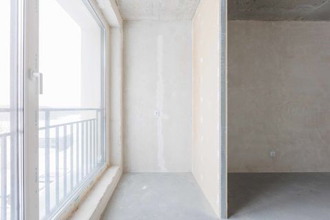 Una habitación vacía con un balcón y una ventana grande.