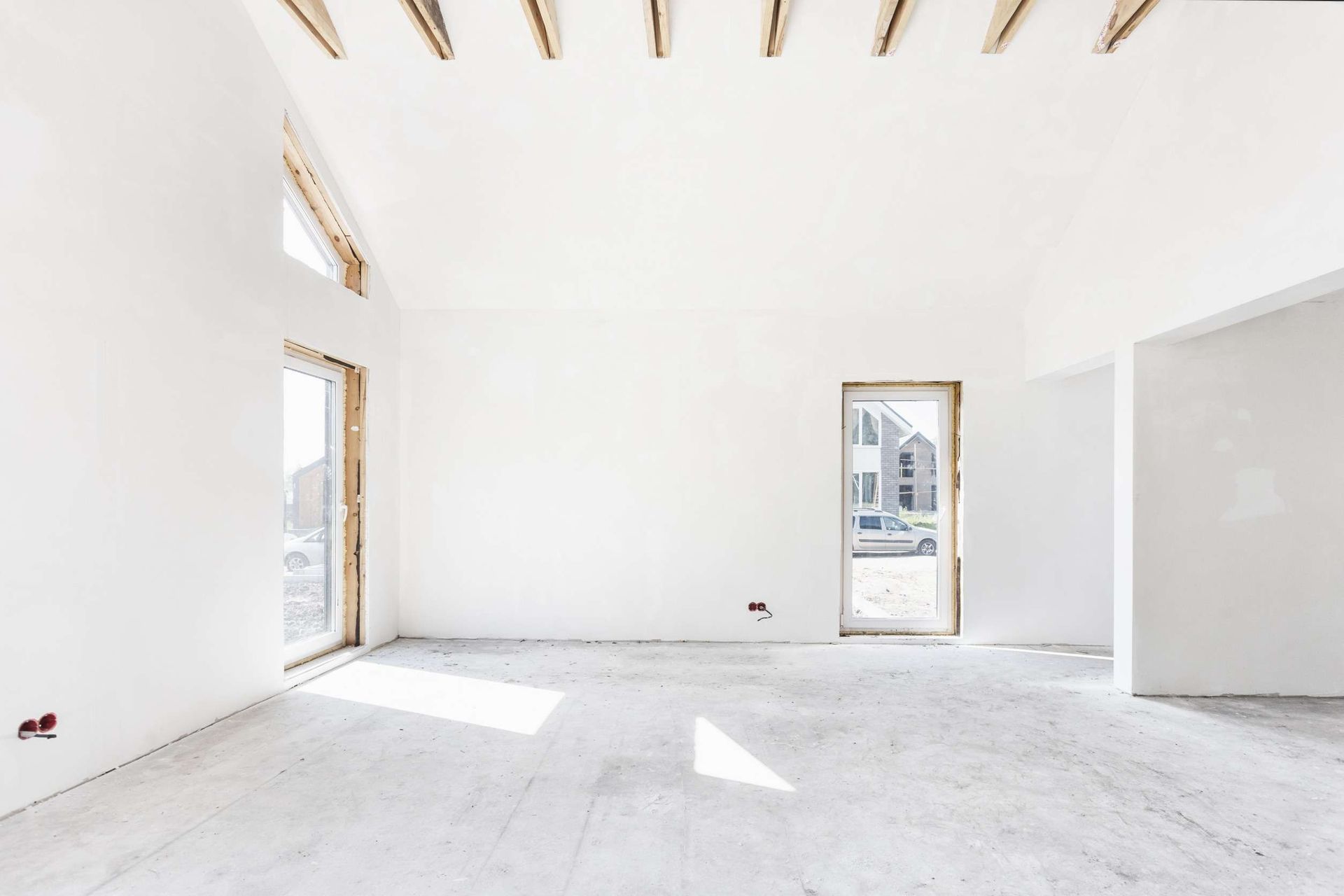 Una habitación vacía con paredes blancas y suelo de hormigón en una casa en construcción.