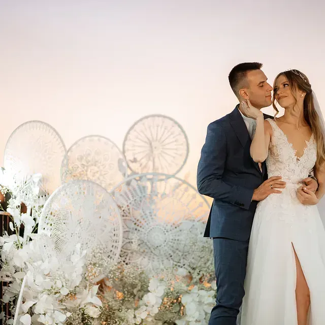 Una novia y un novio se besan delante de una noria.