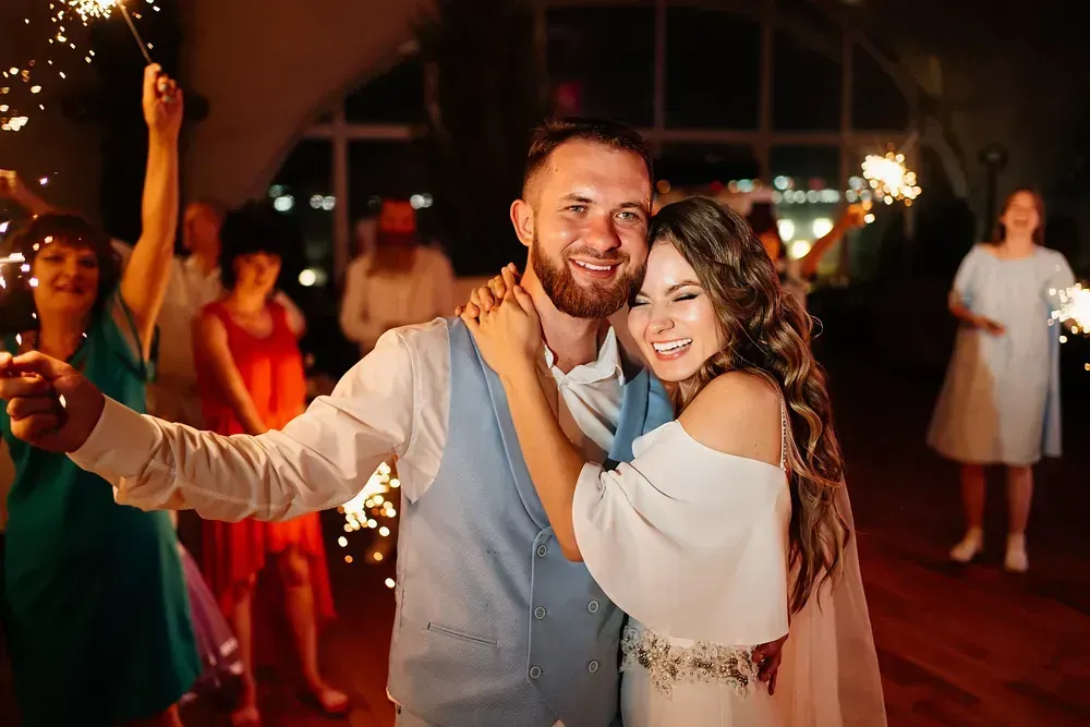 Una novia y un novio están bailando con bengalas en la recepción de su boda.