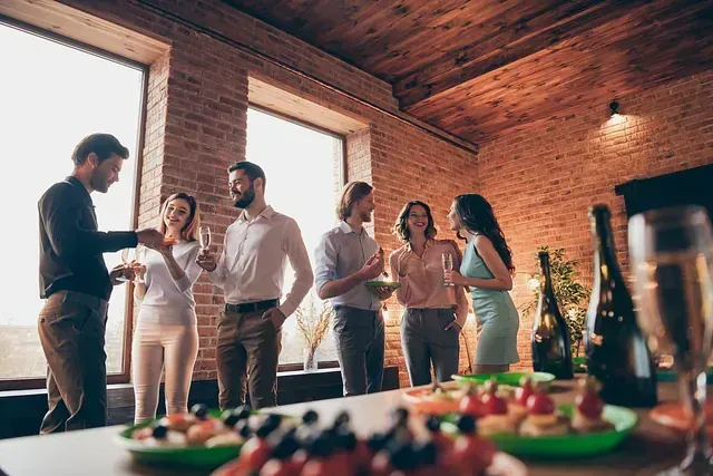 Un grupo de personas están de pie alrededor de una mesa bebiendo champán.