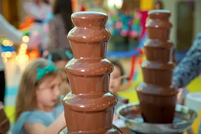 Un grupo de niños está jugando con una fuente de chocolate.