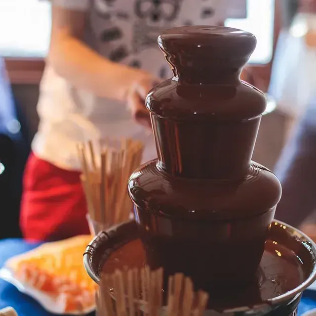 Un primer plano de una fuente de chocolate con palitos dentro.