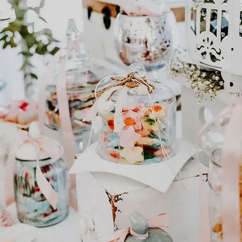 Una mesa cubierta de frascos llenos de dulces y flores.