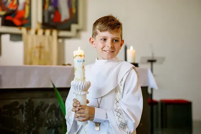 Un niño sostiene una vela en una iglesia.