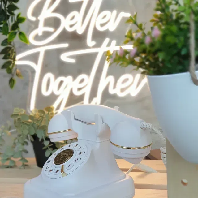 Un teléfono blanco está frente a un letrero de neón que dice 