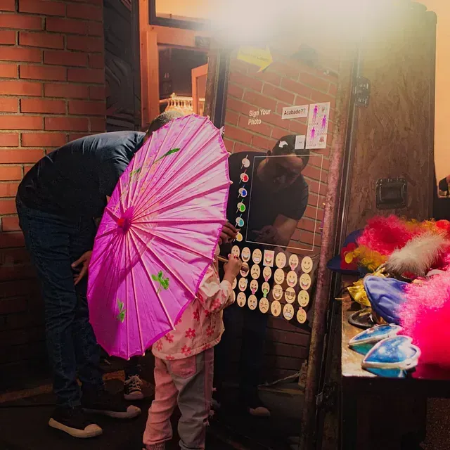 Un hombre y una niña sostienen un paraguas rosa frente a un espejo.